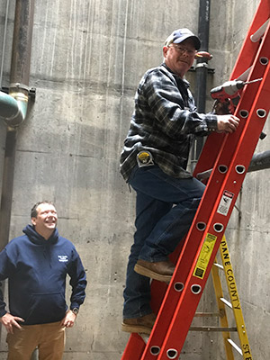 A facilities employee works on a ladder